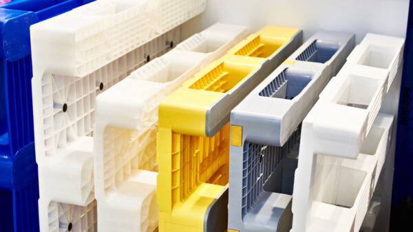 Nestable plastic pallets in white, yellow, gray, and blue stacked together for return shipping