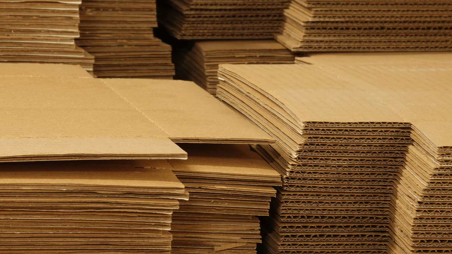 Stacks of flat single wall corrugated cardboard sheets showing the fluted edge profile